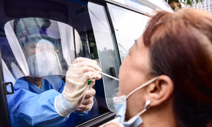 Một nhân viên y tế trong xe chuyên dụng đang xét nghiệm virus Trung Cộng cho cư dân thị trấn Shenyang phía đông bắc Liaoning, Trung Quốc, ngày 7/29/2020 (STR/AFP/Getty Images qua The Epoch Times)