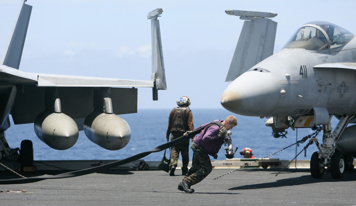 Một thủy thủ đoàn Hải quân Hoa Kỳ kéo ống nhiên liệu qua boong tàu sân bay USS Kitty Hawk (CV63) ở Vịnh Bengal, trong cuộc tập trận Malabar vào ngày 7 tháng 9 năm 2007. (Ảnh Deshakalyan Chowdhury / AFP / Getty Images)