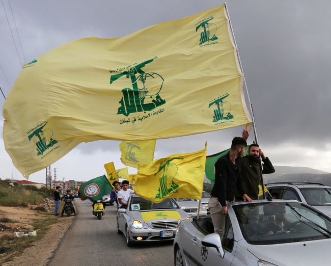 Một người ủng hộ Hezbollah của Li Băng ra cử chỉ khi anh ta cầm cờ Hezbollah ở Marjayoun, Lebanon, vào ngày 7 tháng 5 năm 2018. (Ảnh: Aziz Taher / Reuters)