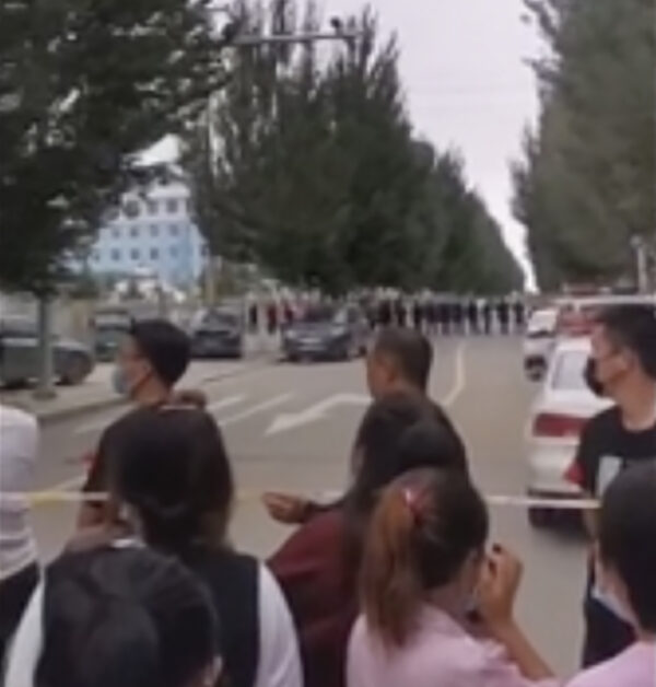 Trong bức ảnh được chụp từ video quay vào tháng 8/2020 này, các phụ huynh tập trung sau hàng rào cảnh sát bên ngoài một trường học ở Tongliao thuộc vùng Nội Mông, vùng Tây Bắc Trung Quốc. (Ảnh AP)