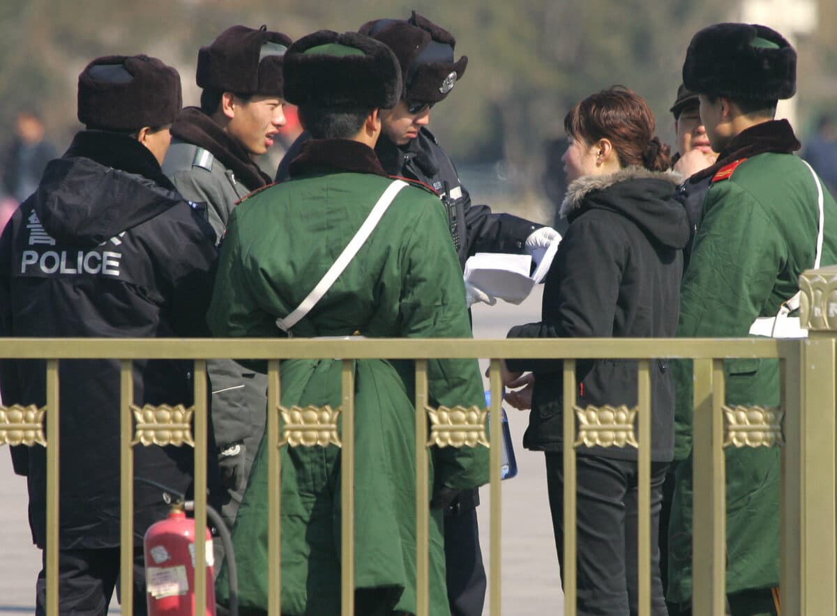 Cảnh sát và lính bán quân sự vây quanh một người phụ nữ trong khi một cảnh sát đọc đơn khiếu kiện của cô trong bối cảnh an ninh được thắt chặt trên Quảng trường Thiên An Môn, Bắc Kinh vào ngày 6/3/2007. (Ảnh Rederic J. Brown/ AFP qua Getty Images)