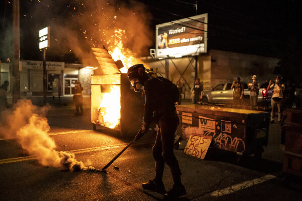 Một người biểu tình đi qua đám cháy vào sáng sớm ngày 29 tháng 8 năm 2020 ở Portland, Oregon. (Ảnh Nathan Howard / Getty)