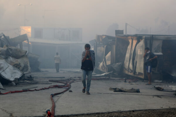 Những người di cư bước đi giữa những khu trú ẩn đã bị phá hủy sau vụ hỏa hoạn tại trại Moria trên đảo Lesbos, Hy Lạp, vào ngày 9/9/2020. (Ảnh Elias Marcou/ Reuters)
