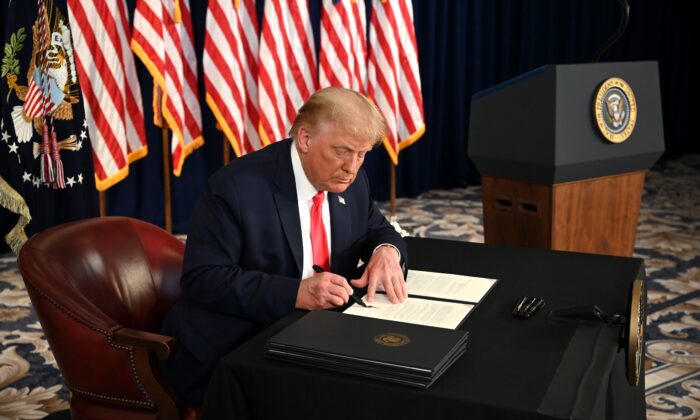 Tổng thống Donald Trump ký sắc lệnh gia hạn gói cứu trợ kinh tế do virus Trung Cộng trong một cuộc họp báo ở Bedminster, New Jersey, vào ngày 8 tháng 8 năm 2020. (Ảnh: Jim Watson/AFP / Getty qua The Epoch Times)