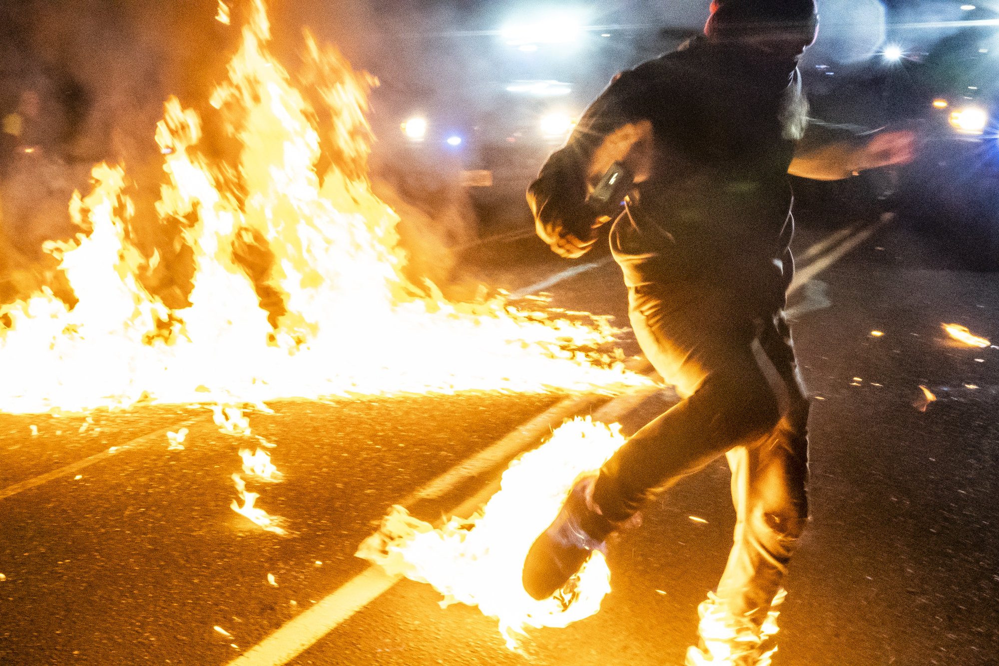 Một người có bàn chân bị bốc cháy sau khi một ly cocktail molotov phát nổ, chạy về phía một nhân viên cứu thương ở Portland, Oregon, vào ngày 5/9/2020. (Ảnh Nathan Howard/Getty Images)