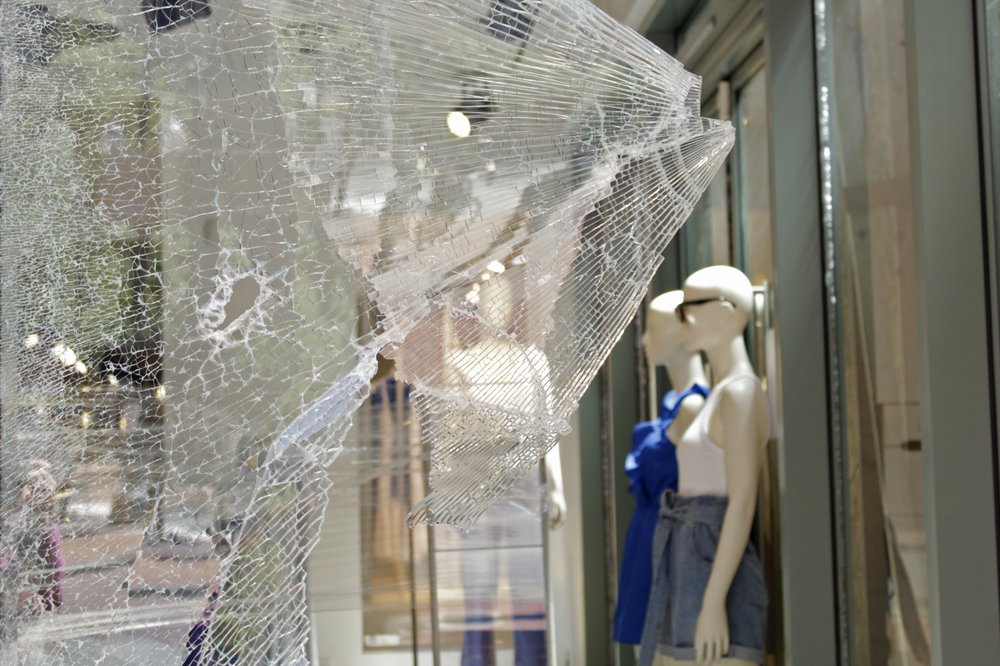 Ma-nơ-canh qua lớp kính vỡ tại một cửa hàng H&amp;M ở trung tâm thành phố Portland, Ore., vào ngày 13 tháng 7 năm 2020. (Ảnh Gillian Flacus / AP)