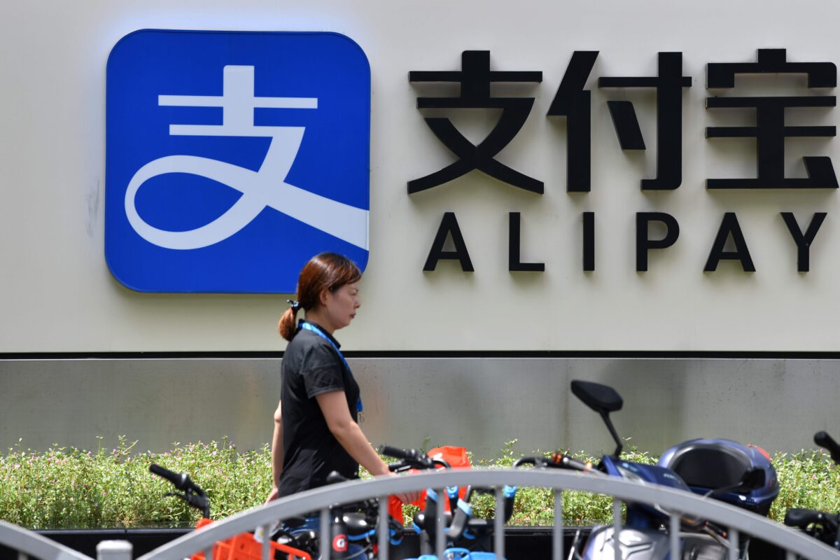 Một khách bộ hành bước ngang qua biển hiệu công ty Alipay tại tòa nhà văn phòng của Ant Group ở Thượng Hải, ngày 28/8/2020. (Ảnh Hector Retamal/ AFP qua Getty Images)