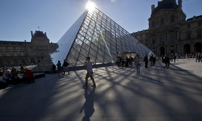 Một người đàn ông đi ngang qua kim tự tháp bằng kính của bảo tàng Louvre ở Paris, Pháp vào ngày 14 tháng 10 năm 2014. (Ảnh Michel Euler / File qua AP)