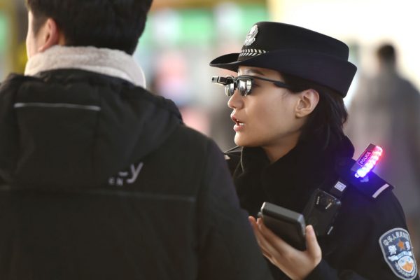 Một sĩ quan cảnh sát (bên phải) nói khi cô đeo kính thông minh có hệ thống nhận dạng khuôn mặt tại ga xe lửa Đông Trịnh Châu ở Trịnh Châu, tỉnh Hà Nam, vào ngày 5 tháng 2 năm 2018. (Ảnh AFP / Getty Images)