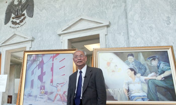 Giáo sư Trương Côn Luân với bức tranh “Tường Đỏ” vẽ từ trải nghiệm của ông khi từng là một tù nhân lương tâm ở Trung Quốc. (Ảnh Ximing / Epoch Times)