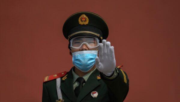 Một sĩ quan cảnh sát bán quân sự Trung Quốc ra hiệu khi đứng gác ở lối vào Tử Cấm Thành ở Bắc Kinh, Trung Quốc, vào ngày 1 tháng 5 năm 2020. (Ảnh Kevin Frayer / Getty Images)