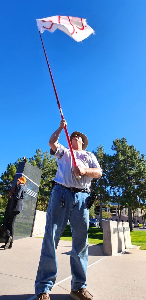 Ông Dan Schroeder ở Phoenix vẫy một lá cờ SOS để bày tỏ sự không tán thành việc tổ chức cuộc bầu cử giữa nhiệm kỳ của Arizona tại một cuộc tập hợp ở Phoenix, hôm 25/11/2022. (Ảnh: Allan Stein/The Epoch Times)