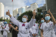 Các nhân viên y tế ở Phúc Châu, thuộc tỉnh Phúc Kiến, miền đông nam Trung Quốc, ra dấu hiệu ủng hộ đồng nghiệp lên đường hỗ trợ phòng chống dịch COVID-19, vào Chủ Nhật, ngày 12/09/2021. (Ảnh: Chinatopix qua AP)