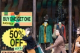Người mua sắm đi ngang qua các biển hiệu giảm giá ở khu vực mua sắm ngoài trời của Avalon trong ngày Thứ Sáu Đen (Black Friday) ở Alpharetta, Georgia, hôm 25/11/2022. (Ảnh: Jessica McGowan/Getty Images)