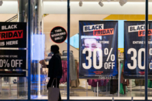 Một người phụ nữ đi ngang qua các biển quảng cáo giảm giá cho ngày Black Friday (Thứ Sáu Đen) ở quận Manhattan của New York vào ngày 26/11/2021. (Ảnh: Jeenah Moon/Reuters)