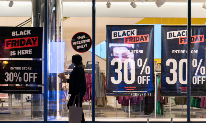 Một người phụ nữ đi ngang qua các biển quảng cáo giảm giá cho ngày Black Friday (Thứ Sáu Đen) ở quận Manhattan của New York vào ngày 26/11/2021. (Ảnh: Jeenah Moon/Reuters)