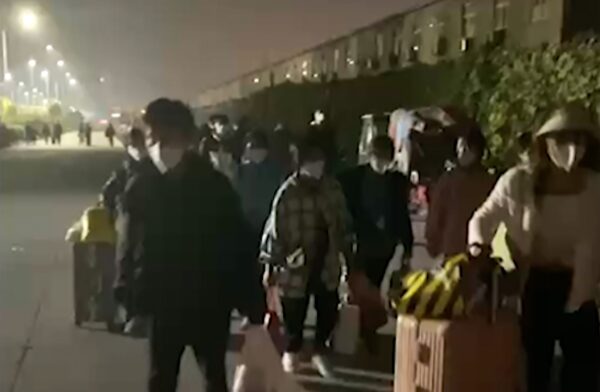 Những người mang theo vali và túi xách rời khỏi khu phức hợp Foxconn ở Trịnh Châu thuộc tỉnh Hà Nam, miền trung Trung Quốc hôm 29/10/2022, trong một bức ảnh chụp từ video. (Ảnh: Hangpai Xingyang qua AP)