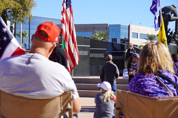 Những người biểu tình ngồi tại chỗ lắng nghe một diễn giả tại một cuộc tập hợp để yêu cầu một cuộc bầu cử giữa nhiệm kỳ mới ở Phoenix, Arizona, hôm 25/11/2022. (Ảnh: Allan Stein/The Epoch Times)