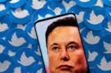 Hình ảnh của ông Elon Musk được nhìn thấy trên một chiếc điện thoại thông minh trên nền các logo Twitter được in hôm 28/04/2022. (Ảnh: Dado Ruvic/Reuters)