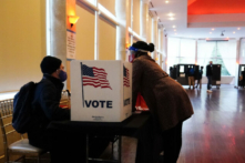 Một nhân viên phòng phiếu nói chuyện với một cử tri trước khi họ bỏ phiếu trên một lá phiếu giấy ở Georgia. (Ảnh: Brynn Anderson/AP Photo)