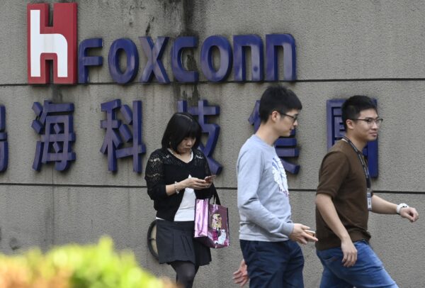 Mọi người đi ngang qua logo Foxconn ở Đài Bắc, Đài Loan, Hôm 31/01/2019. (Ảnh: Sam Yeh/AFP/Getty Images)