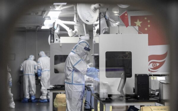 Các kỹ thuật viên phòng thí nghiệm đeo thiết bị bảo hộ cá nhân làm việc trên các mẫu để xét nghiệm COVID-19 tại một cơ sở xét nghiệm ở Vũ Hán thuộc tỉnh Hồ Bắc, miền trung Trung Quốc vào sáng sớm ngày 05/08/2021. (Ảnh: STR/AFP qua Getty Images)