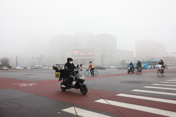 Mọi người đeo khẩu trang khi đi dọc một con phố trong thời tiết sương mù ở Bắc Kinh, Trung Quốc, vào ngày 18/11/2021. (Ảnh: Lintao Zhang/Getty Images)