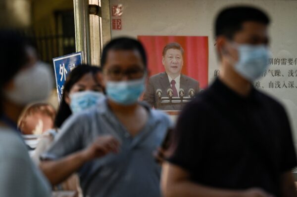 Người dân xếp hàng để được xét nghiệm virus corona COVID-19 bên cạnh tấm bích chương tuyên truyền có hình Chủ tịch Trung Quốc Tập Cận Bình trên bảng thông báo ở Bắc Kinh, hôm 31/08/2022. (Ảnh: JADE GAO/AFP qua Getty Images)