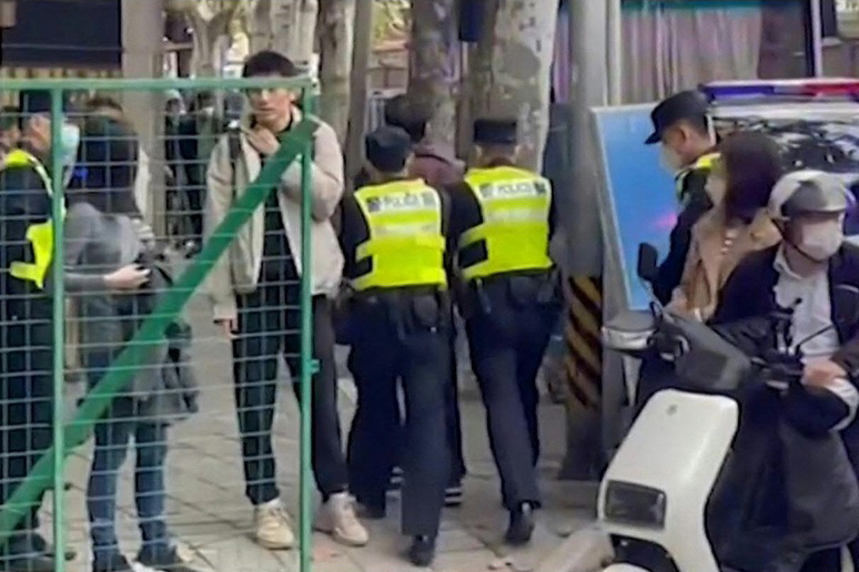 Tấm hình này được lấy từ đoạn video của AFPTV cho thấy công an đang giam giữ một người trên Đường Ô Lỗ Mộc Tề, được đặt tên theo tiếng Quan thoại là Urumqi, ở Thượng Hải hôm 28/11/2022, nơi những người biểu tình tụ tập hồi cuối tuần qua để phản đối các biện pháp hạn chế COVID-19 của Trung Quốc sau một vụ hỏa hoạn tang thương ở Ô Lỗ Mộc Tề, thủ phủ của khu tự trị Tân Cương. (Ảnh: Matthew WALSH/AFPTV/AFP)