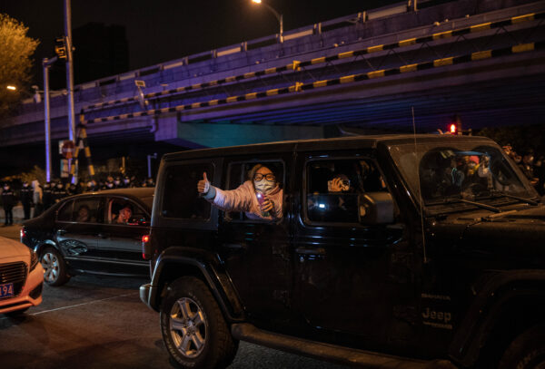 Mọi người thể hiện sự ủng hộ của họ đối với những người biểu tình phản đối các biện pháp nghiêm ngặt zero-COVID của Trung Quốc tại Bắc Kinh hôm 27/11/2022. (Ảnh: Kevin Frayer/Getty Images)