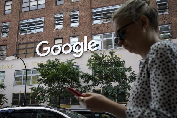 Một người phụ nữ nhìn vào điện thoại thông minh của mình khi đi ngang qua tòa nhà Google ở ​​New York hôm 03/06/2019. (Ảnh: Drew Angerer/Getty Images)