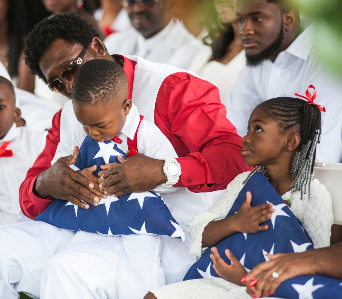 Những đứa con của một Trung sĩ Lục quân Hoa Kỳ La David Johnson, người đã thiệt mạng trong một cuộc phục kích ở Niger, cầm quốc kỳ Mỹ đã gấp lại được trao cho các em trong lễ an táng vào ngày 21/10/2017 tại Hollywood, Florida. (Ảnh: Gaston De Cardenas/Getty Images)