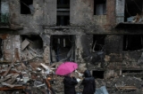 Cư dân địa phương đứng gần tòa nhà của họ bị phá hủy bởi một cuộc tấn công bằng hỏa tiễn của Nga ở thị trấn Vyshhorod, gần Kyiv, Ukraine, hôm 24/11/2022. (Ảnh: Gleb Garanich/Reuters)