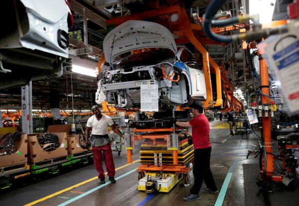 Các công nhân lắp ráp của General Motors kết nối một bộ pin bên dưới chiếc xe Chevrolet Bolt EV 2018 được lắp ráp một phần trên dây chuyền lắp ráp tại Orion Assembly ở Lake Orion, Michigan, ngày 19/03/2018. (Ảnh: Rebecca Cook/Reuters)