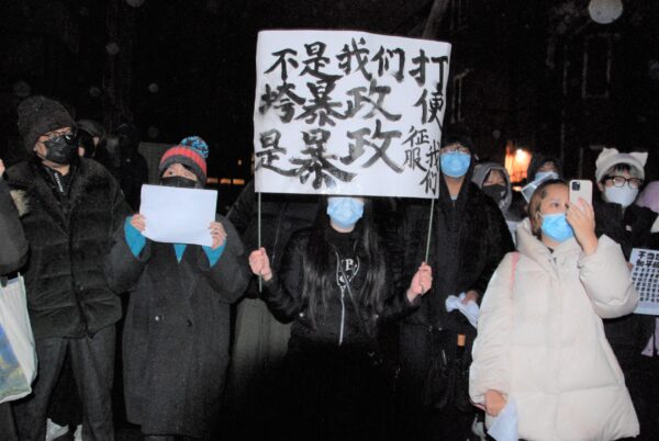 Một người biểu tình cầm tấm biển ghi “Hoặc là chúng ta đánh bại chế độ chuyên chế, hoặc chế độ chuyên chế chinh phục chúng ta” trước lãnh sự quán Trung Quốc ở Toronto hôm 27/11/2022. (Ảnh: Michelle Hu/The Epoch Times)