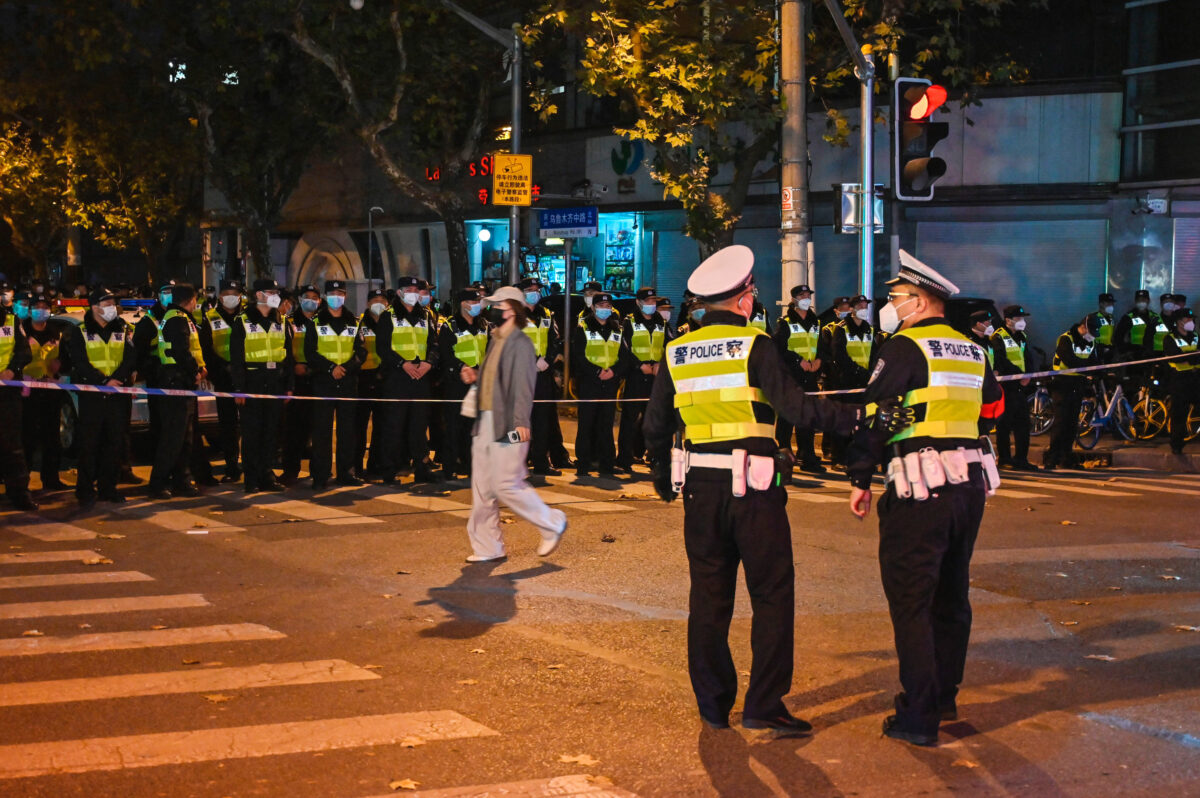 Các sĩ quan cảnh sát phong tỏa phố Wulumuqi (cách nói khác của Ô Lỗ Mộc Tề) ở Thượng Hải hôm 27/11/2022, nơi các cuộc biểu tình phản đối zero COVID diễn ra vào đêm hôm trước để phản hồi một vụ hỏa hoạn gây tử vong ở Urumqi (Ô Lỗ Mộc Tề), Tân Cương. (Ảnh: Hector Retamal/AFP qua Getty Images)