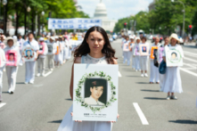 Một người phụ nữ cầm di ảnh của một người đàn ông bị sát hại trong cuộc đàn áp Pháp Luân Công của chính quyền Trung Quốc, trong một cuộc diễn hành ở Hoa Thịnh Đốn hôm 17/07/2014. (Ảnh: Larry Dye/The Epoch Times)