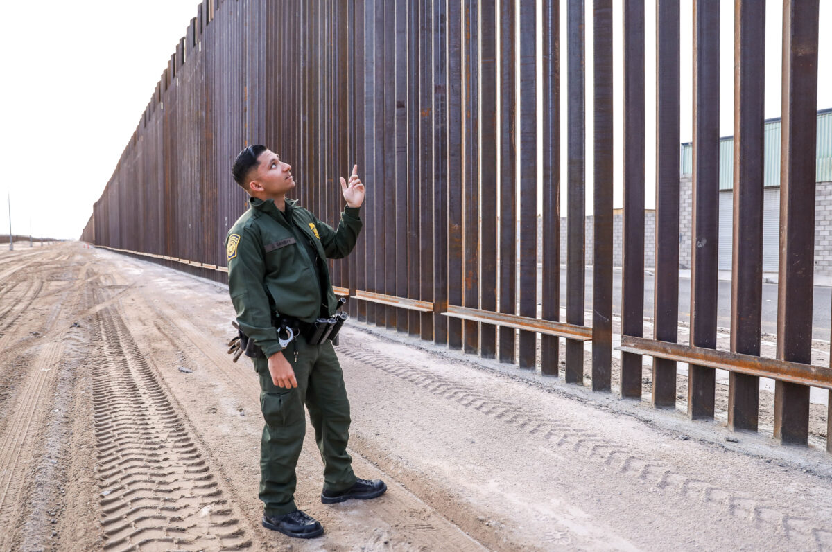 Nhân viên Lực lượng Tuần tra Biên giới Jose Girabay đứng cạnh một phần của hàng rào mới cao 30 foot (9m), dài 22 dặm (35.2km) ở biên giới Hoa Kỳ-Mexico phía đông San Luis ở Yuma, Arizona, vào ngày 27/11/2019. (Ảnh: Charlotte Cuthbertson/The Epoch Times)