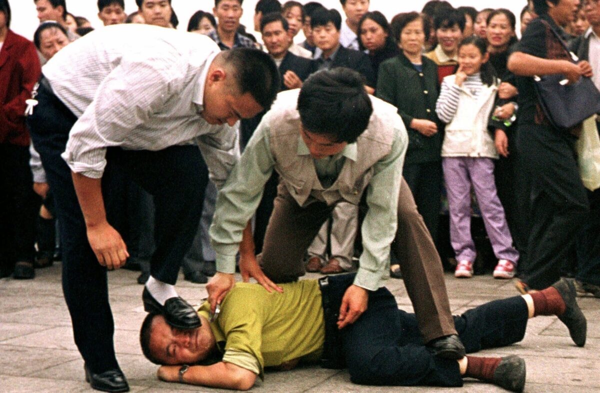 Công an bắt giữ một học viên Pháp Luân Công tại Quảng trường Thiên An Môn trong khi có một đám đông người đứng ngoài quan sát ở Bắc Kinh, trong một bức ảnh được chụp ngày 01/10/2000. (Ảnh: AP/Chien-min Chung)