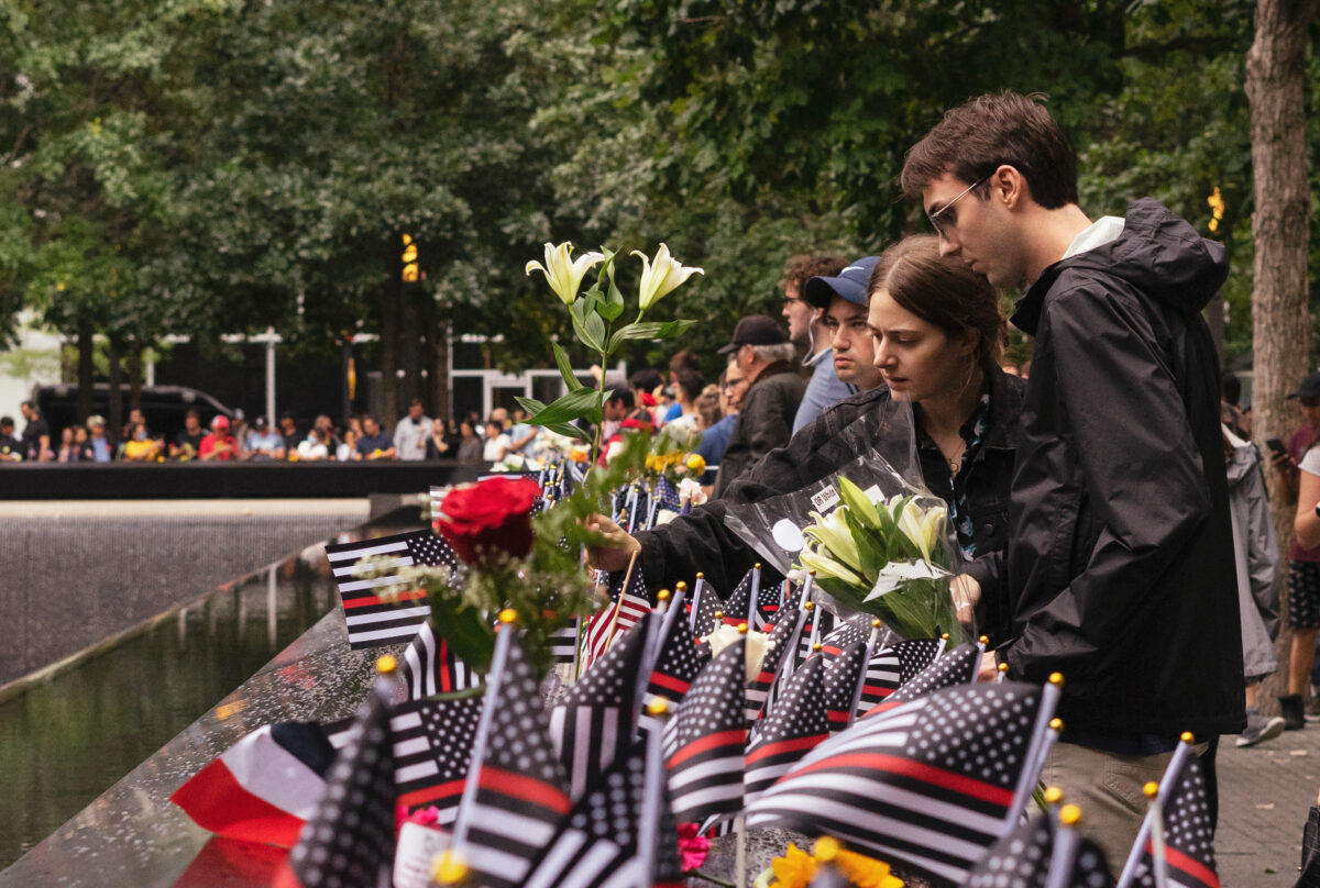Người dân đặt cờ và hoa bên cạnh tên của những người đã thiệt mạng trong vụ tấn công năm 2001, tại Đài tưởng niệm Trung tâm Thương mại Thế giới ở New York hôm 11/09/2022. (Ảnh: Chung I Ho/The Epoch Times)