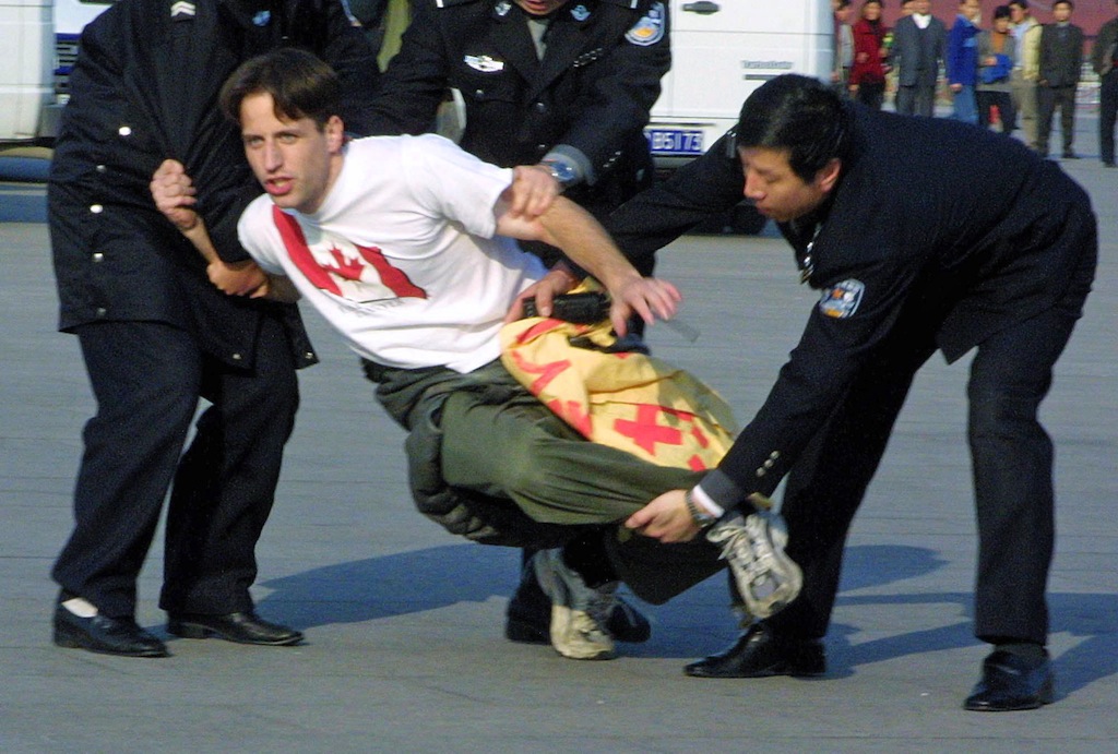 Anh Zenon Dolnyckyj bị cảnh sát Trung Quốc vật ngã tại Quảng trường Thiên An Môn sau khi tham dự một cuộc biểu tình tĩnh tọa ủng hộ Pháp Luân Công vào ngày 20/11/2001. Khoảng 20 người phương Tây đã tham dự cuộc biểu tình tĩnh tọa bày và giương một biểu ngữ lớn trước khi bị công an bắt giữ. (Ảnh: AP Photo/Ng Han Guan)