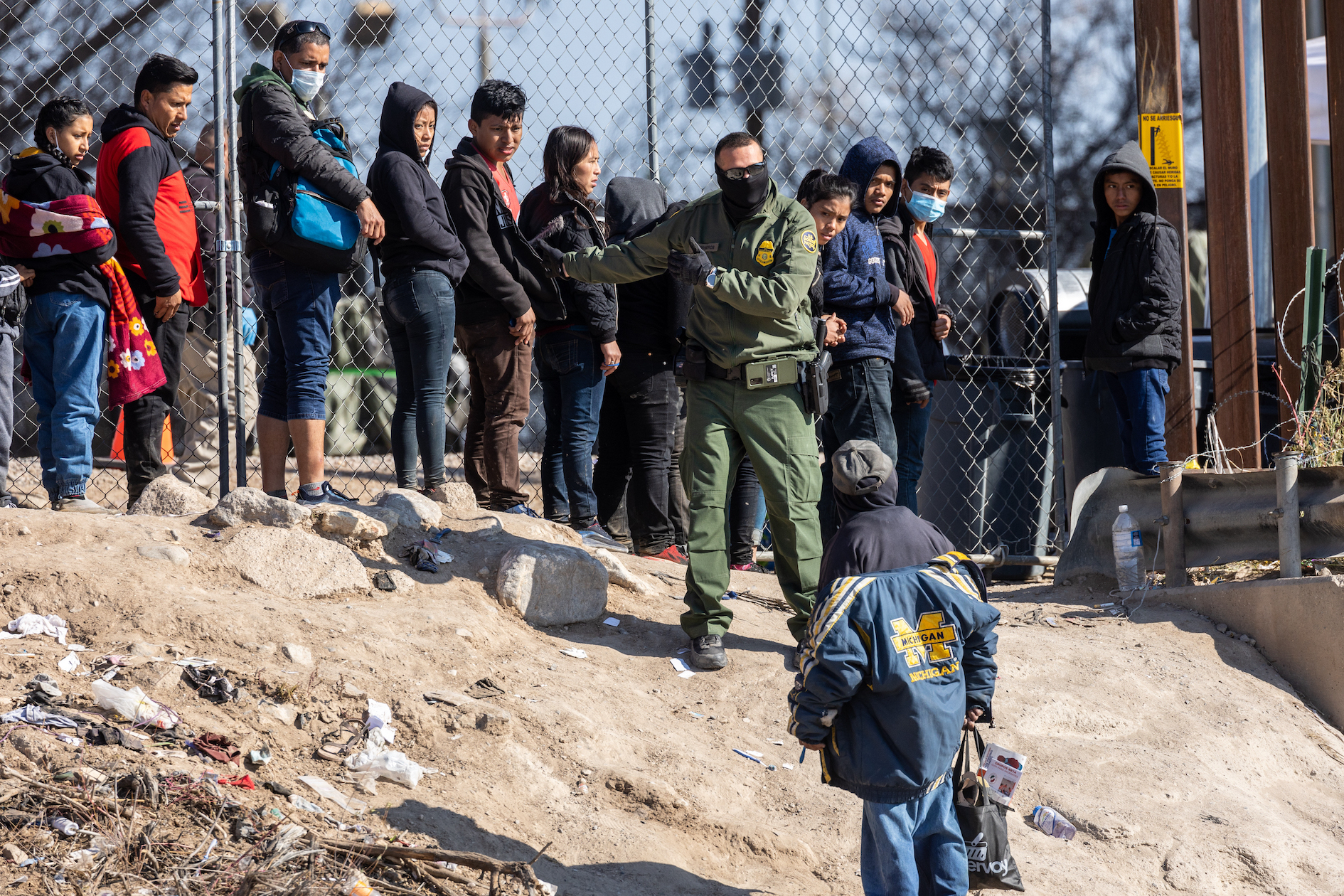 Một nhân viên của Lực lượng Tuần tra Biên giới Hoa Kỳ hướng dẫn những người nhập cư đã vượt qua sông Rio Grande đến tiến vào thành phố El Paso, Texas, nhìn từ phía thành phố Ciudad Juarez, Mexico, hôm 19/12/2022. (Ảnh: John Moore/Getty Images)