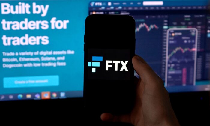Ảnh minh họa này chụp một màn hình điện thoại thông minh có logo của nền tảng giao dịch mã kim FTX, đằng sau là một màn hình hiển thị trang web FTX ở Arlington, Virginia, hôm 10/02/2022. (Ảnh: Olivier Douliery/AFP/Getty Images)