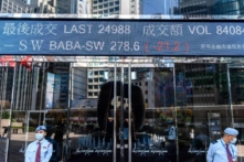 Hoạt động chứng khoán của Alibaba Group Holding Ltd. (BABA-SW) (trên cùng ở giữa) được hiển thị phía trên các nhân viên bảo vệ khi họ đứng bên ngoài tòa tháp Exchange Square ở Hồng Kông vào ngày 04/11/2020. (Ảnh: Anthony Wallace/AFP qua Getty Images)