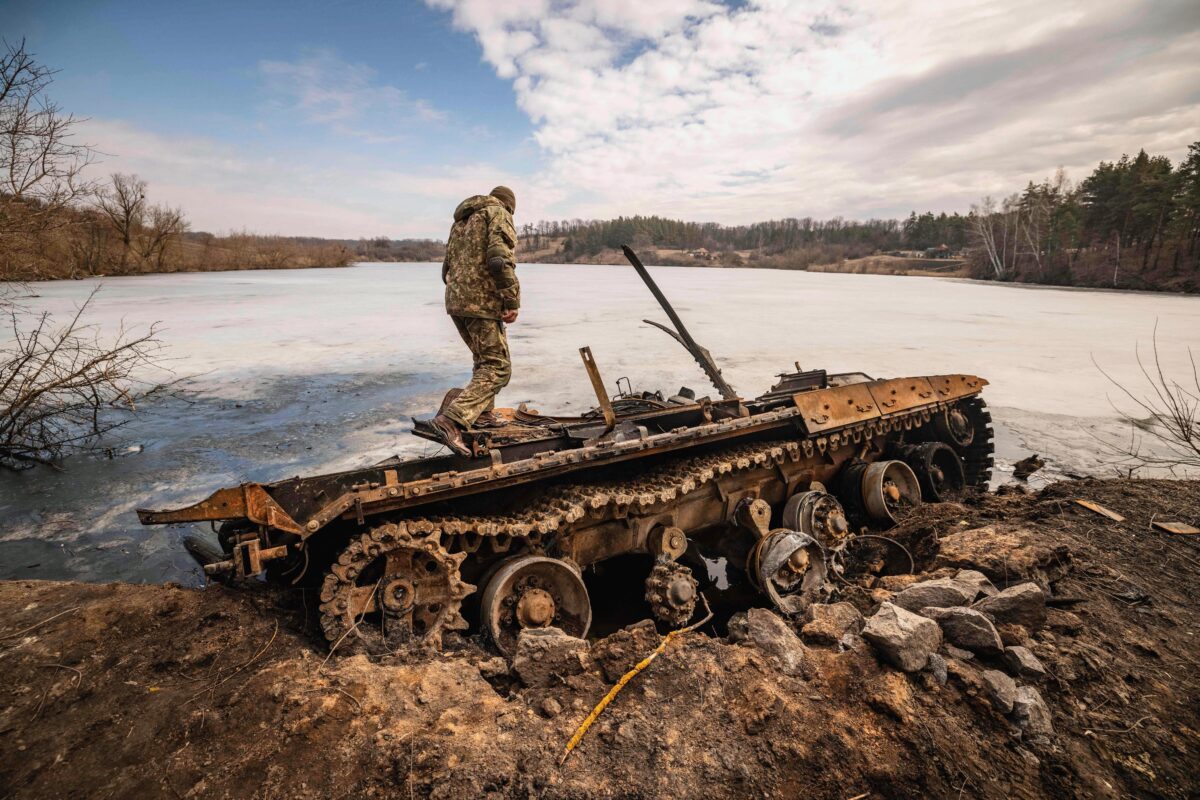Một quân nhân Ukraine đứng trên chiếc thiết vận xa Nga bị phá hủy ở thành phố Trostyanets phía đông bắc Ukraine sau khi Ukraine tuyên bố rằng họ đã tái chiếm thị trấn này; một trong những nơi đầu tiên nằm dưới sự kiểm soát của Moscow, hôm 29/03/2022. (Ảnh: Fadel Senna/AFP qua Getty Images)