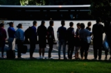 Những người di cư bất hợp pháp trên chuyến xe buýt xuất phát từ Texas đang lắng nghe các tình nguyện viên đề nghị trợ giúp sau khi được cho xuống xe, có thể được nhìn thấy từ tòa nhà Capitol Hoa Kỳ ở Hoa Thịnh Đốn hôm 11/08/2022. (Ảnh: Stefani Reynolds/AFP qua Getty Images)