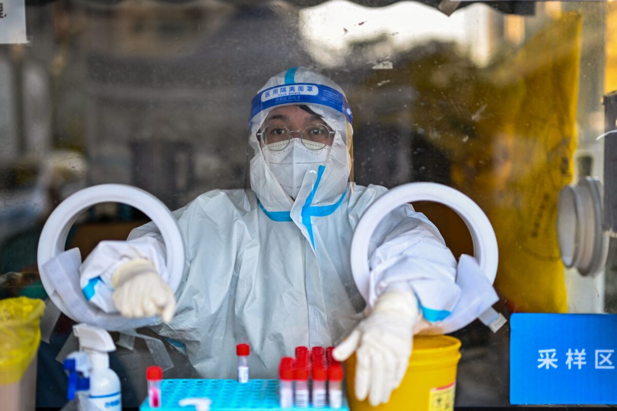 Một nhân viên y tế ngồi chờ người dân đến lấy mẫu dịch tỵ hầu để tầm soát virus corona COVID-19 tại Thượng Hải, hôm 19/12/2022. (Ảnh: Hector Retamal/AFP qua Getty Images)