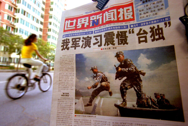 Một tờ báo đăng hình các binh sĩ của Quân Giải phóng Nhân dân (PLA) trong một cuộc tập trận quân sự với tiêu đề “Cuộc tập trận quân sự của Trung Quốc khiến những người ủng hộ độc lập phải chấn kinh,” tại Bắc Kinh, hôm 07/08/2002. (Ảnh: Kevin Lee/Getty Images)