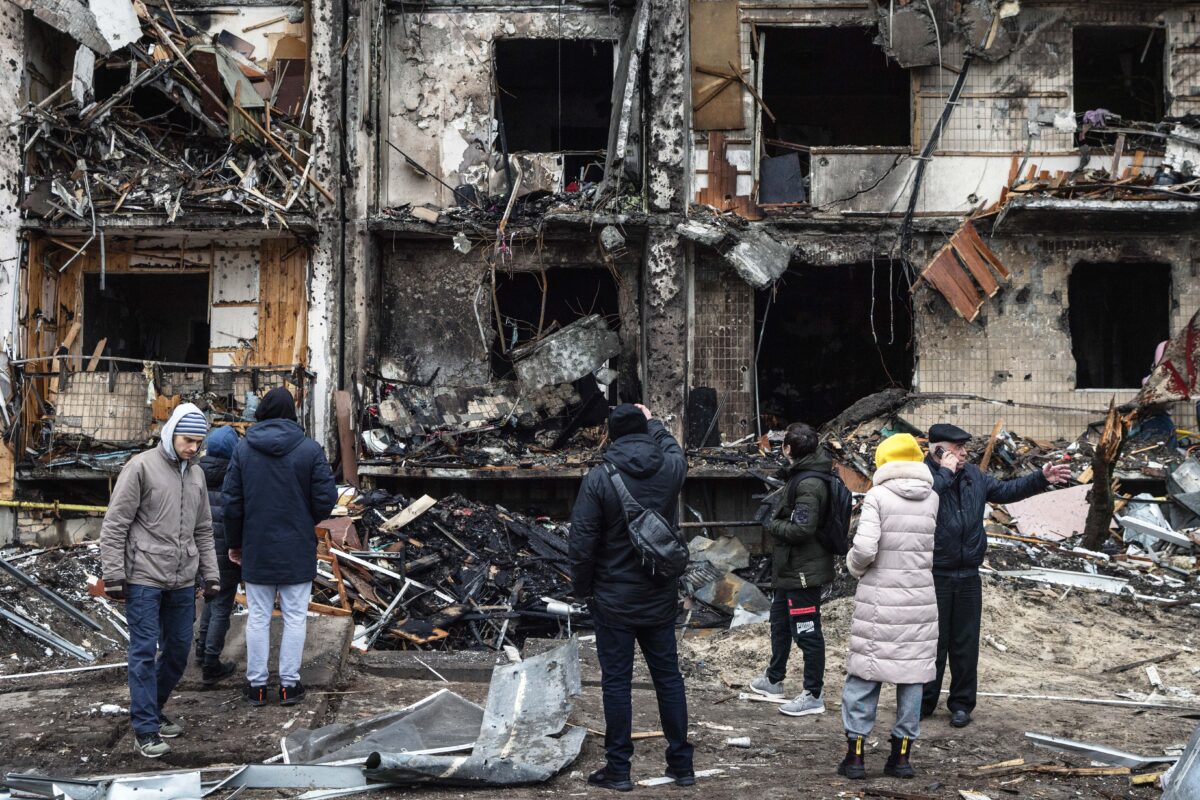 Mọi người nhìn vào bên ngoài một khu dân cư bị hư hại do trúng hỏa tiễn vào sáng sớm ở Kyiv, Ukraine, hôm 25/02/2022, một ngày sau khi Nga tiến hành một cuộc tấn công quy mô lớn vào quốc gia này. (Ảnh: Chris McGrath/Getty)