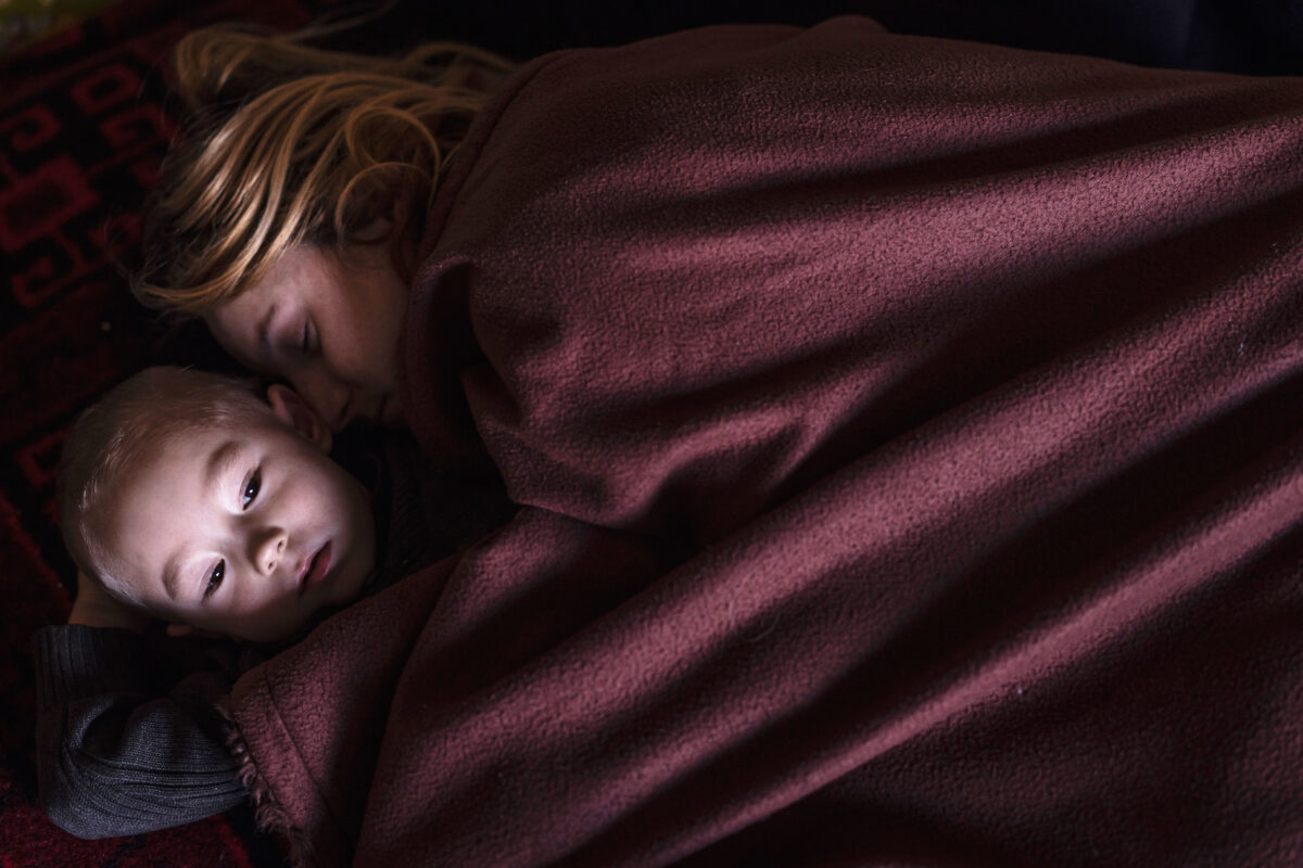 Một người mẹ và con trai ngủ trong một khu gia đình ở Lviv, Ukraine, trong khi chờ lên tàu tới Ba Lan. Hơn 2 triệu người đã đào thoát khỏi Ukraine trong ba tuần qua, hôm 12/03/2022. (Ảnh: Dan Kitwood/Getty Images)